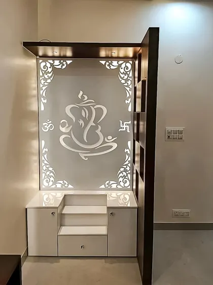 A compact and modern pooja unit with a backlit Ganesha design on an acrylic panel. The white base cabinet provides storage for pooja items, making it perfect for an apartment.