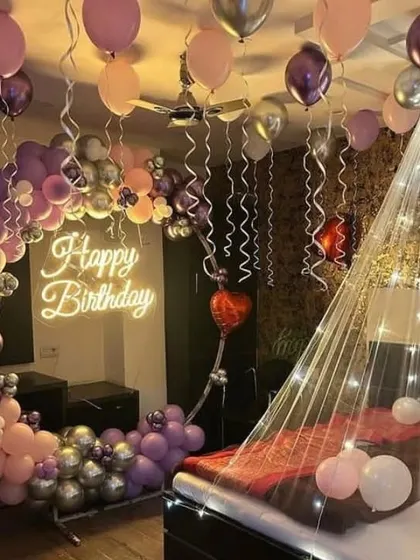 Transform any bedroom into a romantic birthday retreat. This surprise decoration includes a beautiful balloon half-arch, ceiling balloons with ribbons, a glowing neon sign, and a fairy light canopy over the bed for a magical atmosphere.