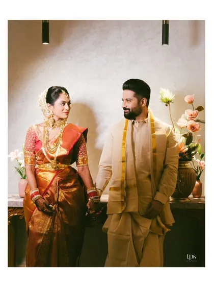 A classic portrait of the couple holding hands. Their matching traditional outfits and happy expressions create a perfect wedding day memory.