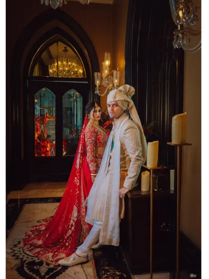 A powerful and regal portrait of the couple in a grand, candle-lit hallway.