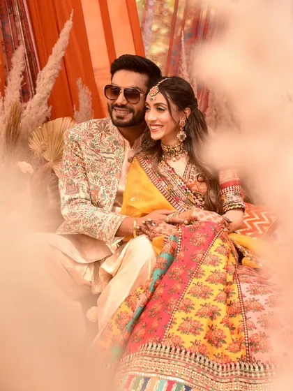 A dreamy, soft-focus shot of the couple at their Mehndi. The warm tones and beautiful outfits create a picture of pure romance.