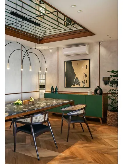 The dining area in the "Blue" apartment features a custom-beveled mirror ceiling that enhances the volume of the space. A beautiful marble-topped table is paired with classic cane chairs and a modern green credenza.