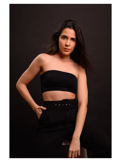 A minimalist and modern fashion portrait. The simple black outfit and dark background create a sleek and sophisticated look.