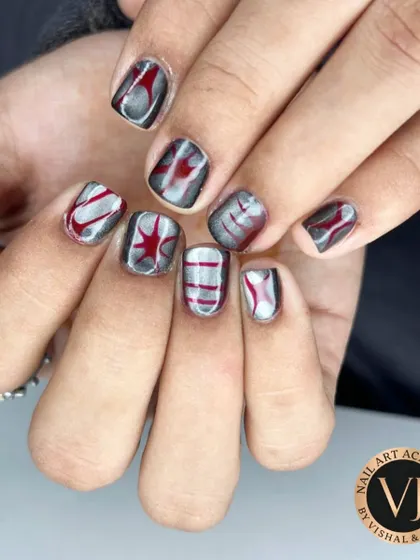 A close-up of the finished abstract metallic nail art. The combination of silver, black, and red creates a futuristic and graphic look, with each nail featuring a unique, hand-painted pattern.