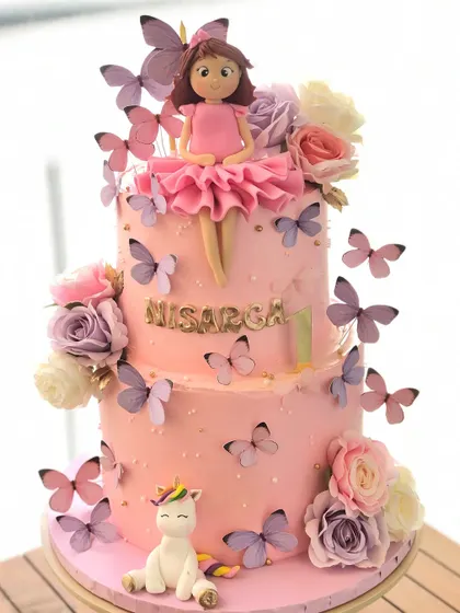 A beautiful two-tiered cake featuring a doll, a unicorn, and a cascade of purple butterflies.