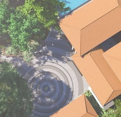 A top-down view of the bungalow, showing how the tiled roofs and building masses are arranged to harmonize with the surrounding trees and landscape.
