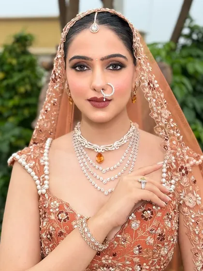 A direct, confident look from the bride. Her makeup is powerful yet elegant, with perfectly defined brows and a bold lip that commands attention.