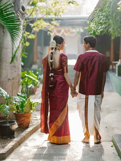 The couple, dressed in traditional South Indian attire, walking hand-in-hand through the heritage venue. This image perfectly captures the beautiful blend of two worlds coming together.