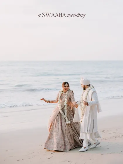 A serene portrait of the couple walking hand-in-hand on the beach after their ceremony, dressed in elegant white and pastel attire.