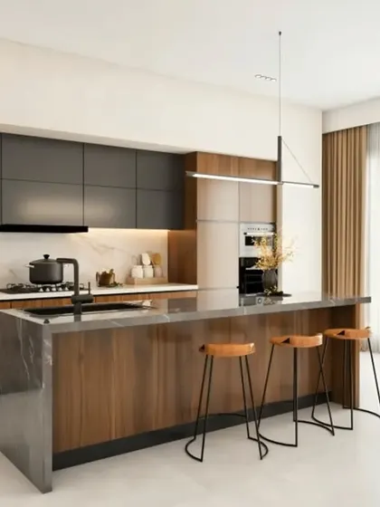 A luxurious kitchen featuring a large island with a waterfall countertop that doubles as a breakfast bar. The combination of dark grey and wood-finish cabinets provides a sophisticated and warm aesthetic.