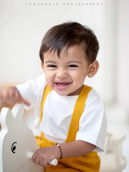 A giggle that's pure gold. This happy boy is having the time of his life on the rocking horse in our simple and classic studio setup.