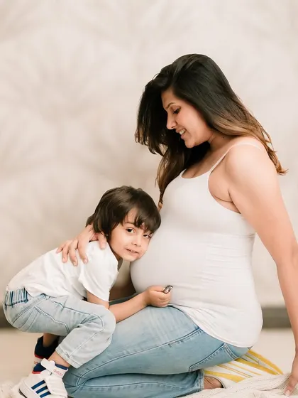 A soon-to-be big brother listens to his mommy's belly, a sweet and classic maternity pose.