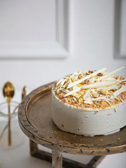 Our Vanilla Raspberry ice cream cake, topped with white chocolate shards and toasted pistachios. The alternating layers of vanilla sponge and raspberry sorbet create a refreshing delight.