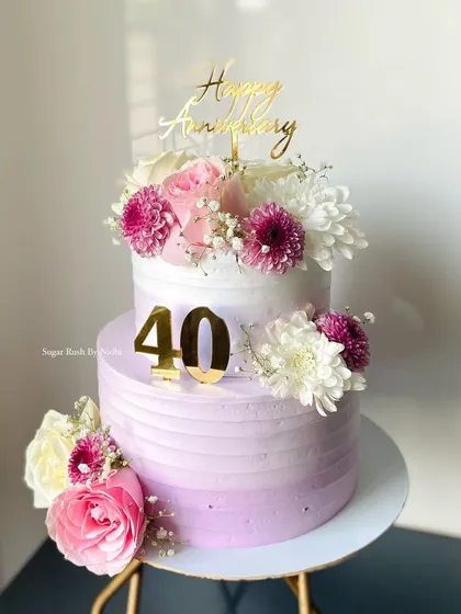 Celebrating 40 years together with this stunning two-tiered anniversary cake. The lavender ombre design is decorated with an assortment of fresh flowers for a truly special milestone.