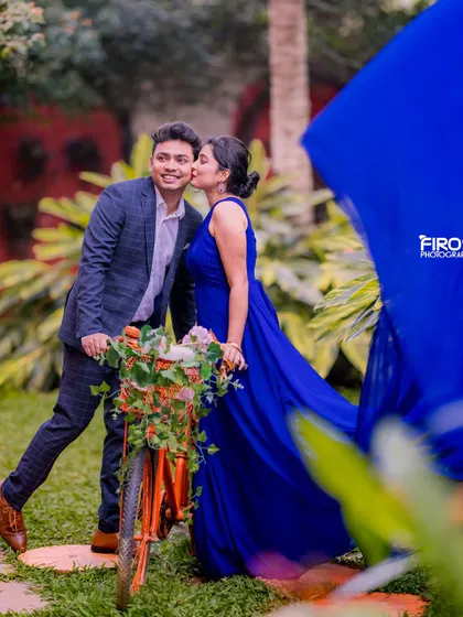 A playful kiss on the cheek while the groom is on a bicycle. The bride's flowing blue gown adds a touch of elegance to this fun, candid moment.