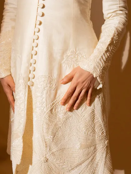 A detailed shot of the intricate embroidery and button detailing on the ivory suit. This is what couture is all about.