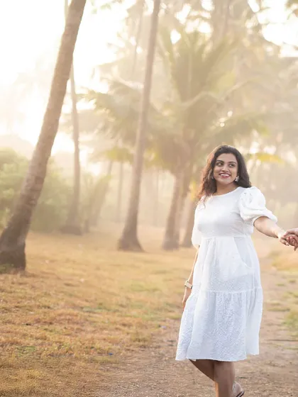 A "follow me to" style pre-wedding shot, with the bride-to-be leading her partner through a beautiful, sunlit path lined with palm trees.