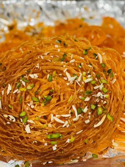 For those looking for something beyond the ordinary, we offer specialty sweets like this intricate Ghevar. It's a crispy, delicate dessert, garnished with nuts, that adds a wow factor to any festive occasion.