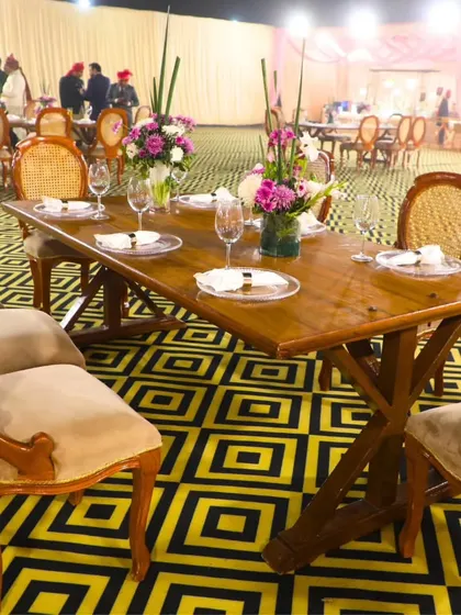 An outdoor dining setup with wooden tables and classic chairs on a patterned floor. We can create beautiful and comfortable dining spaces for any event, indoors or out.