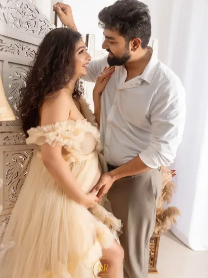A candid and romantic moment from a boho-chic maternity session. The soft, natural light and neutral tones create a relaxed and intimate atmosphere.