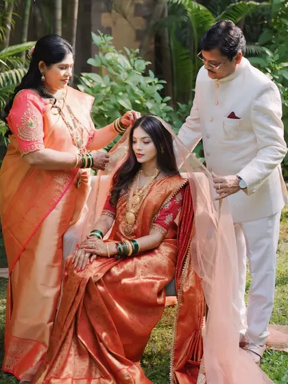A heartwarming moment with her parents. This image captures the love and blessings as they place the dupatta on her head, a significant pre-ritual moment.