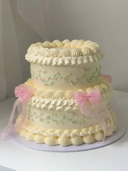 Another angle of the two-tiered vintage buttercream cake, showcasing the intricate ruffles and delicate floral piping that give it a classic, romantic feel.