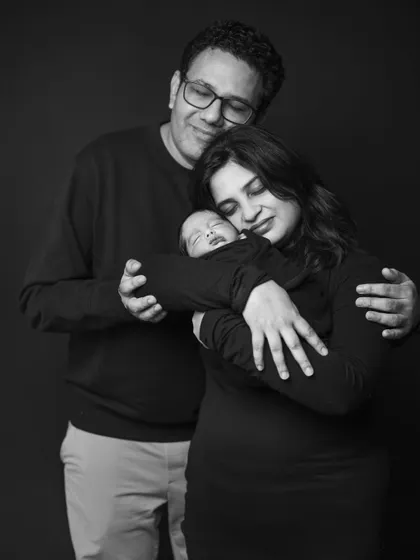 A moment of pure bliss for new parents. This black and white photo captures the family in a loving embrace, with their newborn held safely between them.