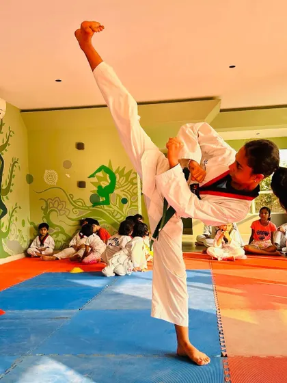 A powerful high kick captured from a different angle, showing the student's focus and strength.