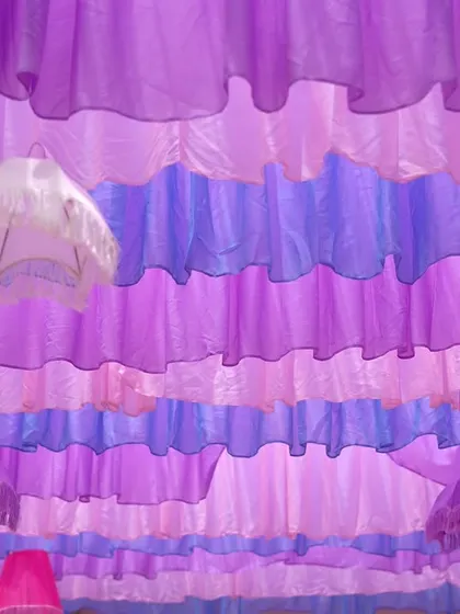 A close-up of the ceiling decor. We created a unique texture with layers of ruffled drapes in different pastel shades, with playful lampshades peeking through for a whimsical touch.