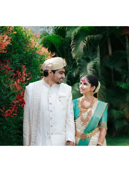 A classic couple portrait from a South Indian wedding, with the bride and groom sharing a look of love amidst a colorful garden setting.
