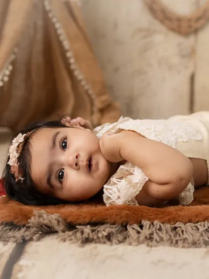 A moment of quiet wonder. This side-profile shot captures the baby's curiosity as she lies in a boho-themed setup.