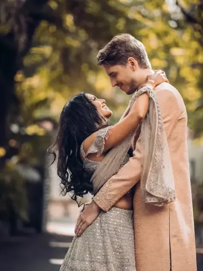 A happy, dancing pose from a multicultural couple, blending traditional Indian attire with a joyful, modern energy.
