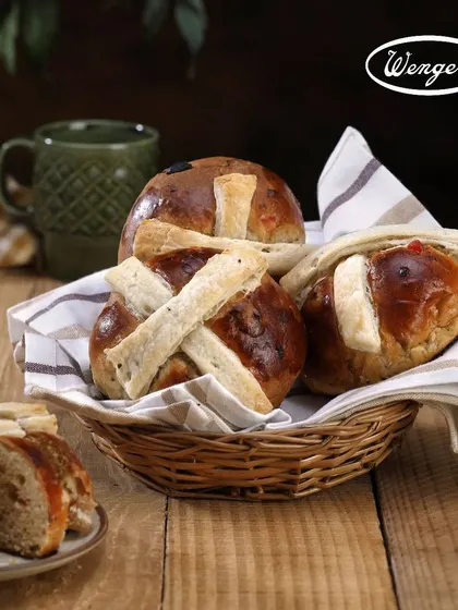 A basket full of our freshly baked Hot Cross Buns, ready to be shared. This image captures the soft texture and rich color of these spiced sweet buns, a true sign of Easter at Wenger's.