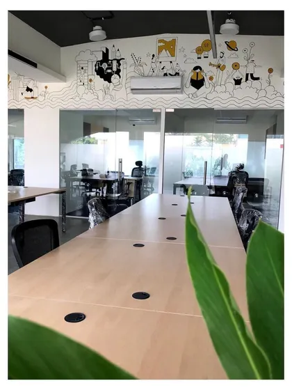 An office interior designed for a modern workspace, featuring glass partitions for an open feel and a custom hand-illustrated mural that adds a unique artistic element. The design balances professionalism with creative energy.