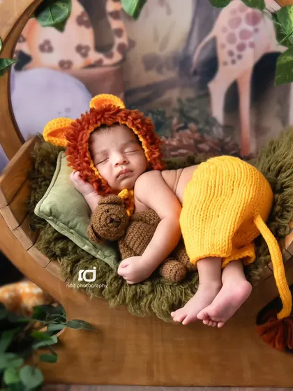 Cuddling a teddy bear, our little Simba is sleeping soundly in his jungle-themed swing.
