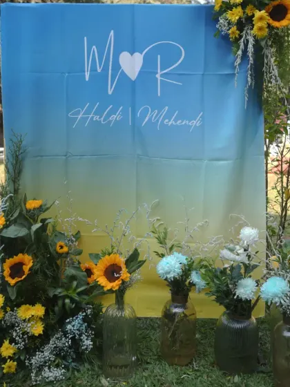 A personalized welcome sign for Moksha and Rahill's Haldi and Mehendi, with a blue and yellow ombre design, framed by sunflowers.