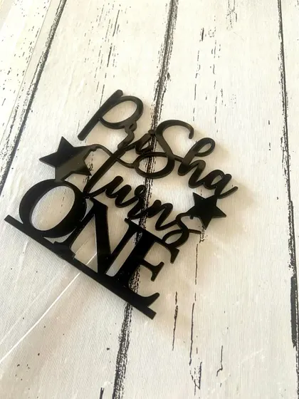 A flat-lay of the "Prisha turns ONE" topper, showing the clean edges and quality of the acrylic cut.