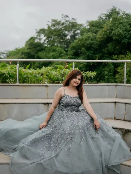 The long, flowing trail of the grey gown creates a stunning visual, especially when seated on stairs.