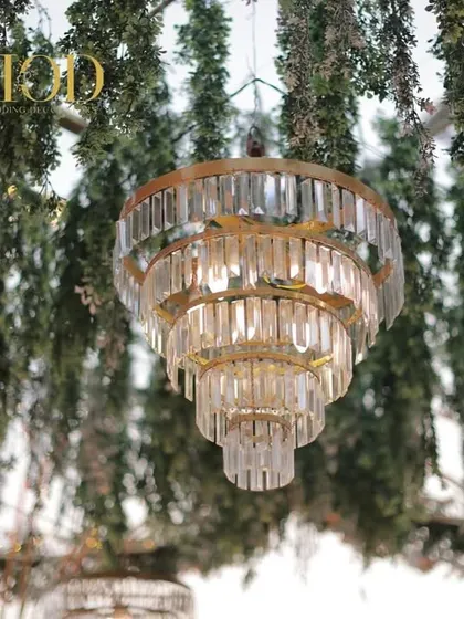 A close-up of a beautiful tiered crystal chandelier, a key artistic detail that adds a touch of luxury and sparkle to the wedding decor.