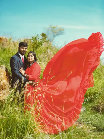 A close-up of a couple in a field, where the bride's flowing red dress adds a pop of color and drama to the natural surroundings. This is a beautiful shot for a save-the-date announcement.