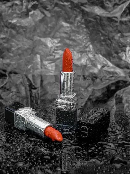 A creative take on a classic product. This shot uses a color-pop technique, with the red lipstick standing out against a monochrome textured background, for a modern and artistic feel.