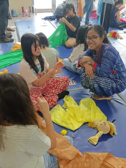 Students work together, sharing colorful fabrics to create clothes for their puppets. This is a great activity for learning and collaboration.