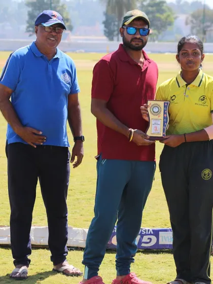 A player receives her award from the coach and a senior official.