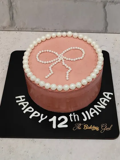 A pretty and elegant cake for a 12th birthday. The dusty rose color is complemented by a pearl bow and border, creating a chic and timeless design.