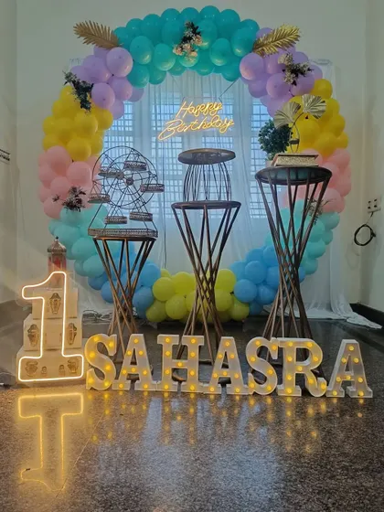 A view of the pastel first birthday setup with the marquee lights turned on. The glowing letters and number add a warm and celebratory feel to the entire decoration.