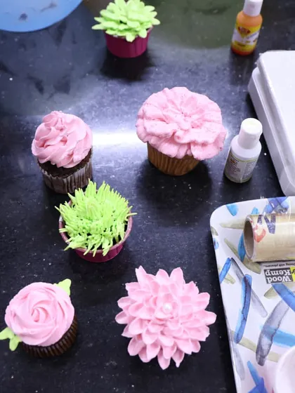 A view of my workstation during a cupcake workshop. You can see various floral and succulent-style cupcake designs, along with the tools of the trade.