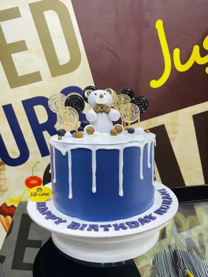 A stylish 2kg drip cake in royal blue, topped with a classy fondant teddy bear.