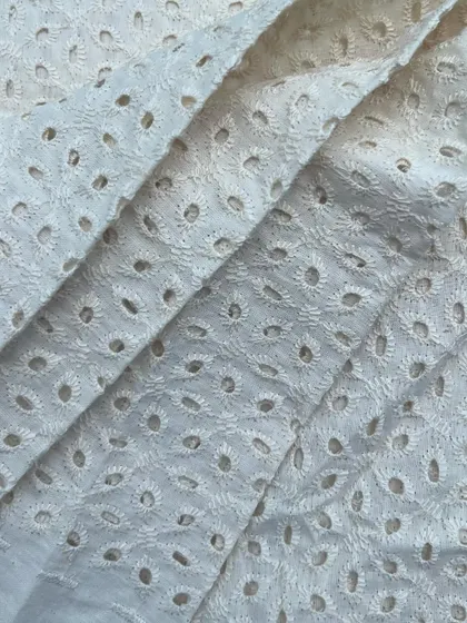 A close-up of our white cutwork cotton fabric, showcasing the delicate and intricate embroidery that adds a touch of sophistication.