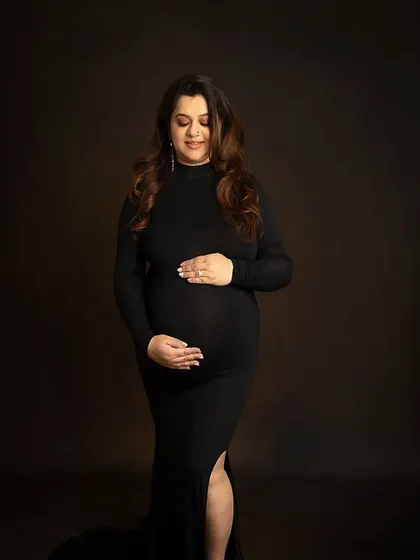 A classic three-quarter portrait in a simple black gown. This pose is elegant, timeless, and beautifully showcases the baby bump.