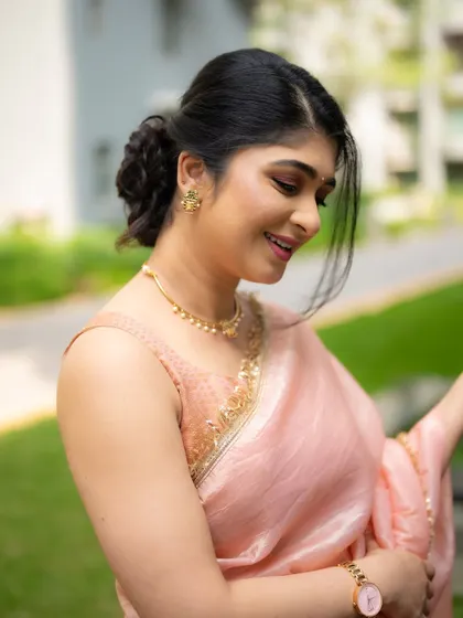 A candid shot of an actress in a delicate pink organza saree. The soft, natural light and her gentle smile create a graceful and feminine portrait.
